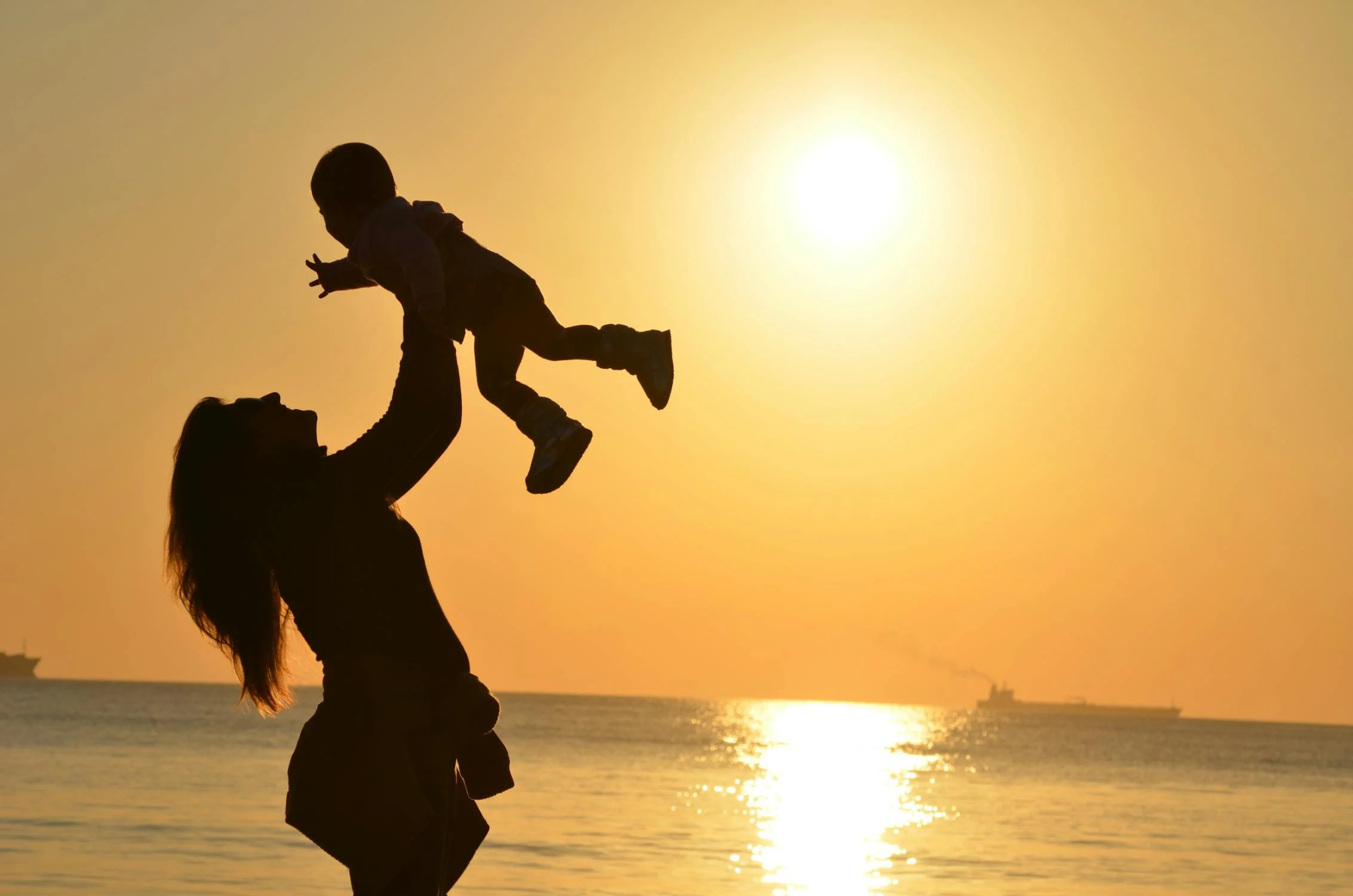 Mère et bébé sur une plage au coucher du soleil